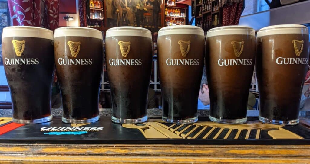 Six pints of Guinness lined up on the bar. 'Black stuff is one of the most popular Irish slang phrases.