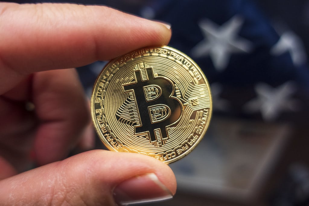 Picture of a hand holding a physical bitcoin.