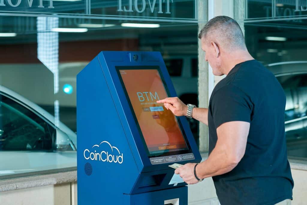Picture of a man using a bitcoin ATM, used to explain the rise of bitcoin ATMs in Ireland: Where they are and what to expect.