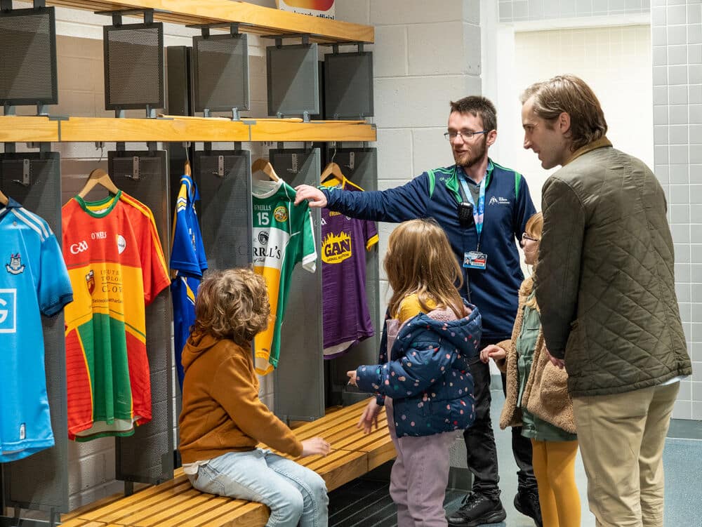 Picture of an Irish man and kids looking at some GAA kits. Used to explain why Ireland is obsessed with GAA.