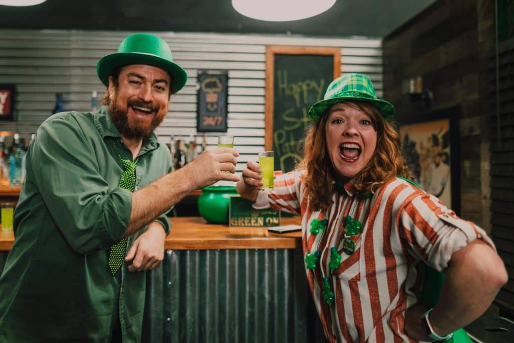 Picture of a happy Irish-American man and woman cheering with drinks.