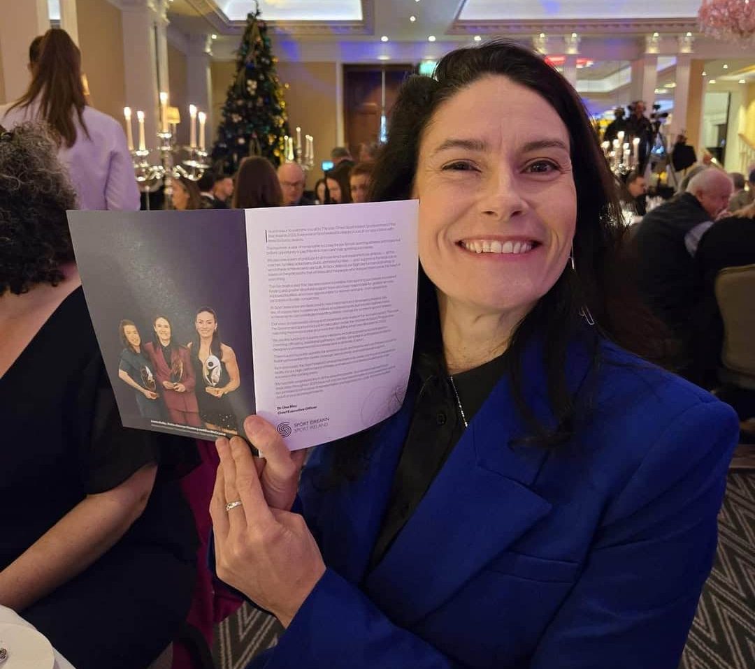 Katie-George Dunlevy posing beside an awards ceremony leaflet with her featuring on it.