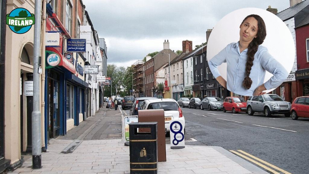 A quiet, ordinary street in Lisburn filled with parked cars and shops, featuring an inset of a woman looking bored and unimpressed.