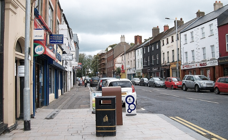 A tranquil view of Bow Street in Lisburn showing a row of local shops, pedestrian pavements, and a grey, overcast sky.