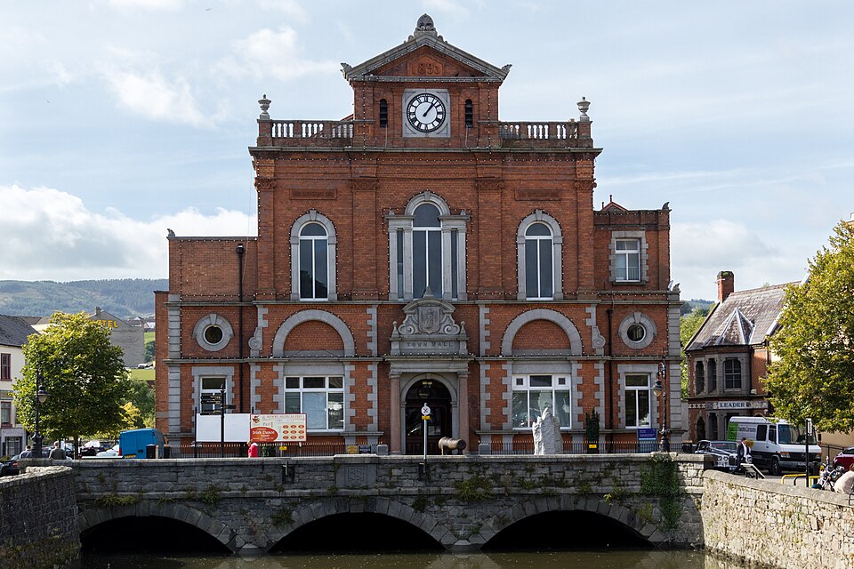 The historic red-brick Newry Town Hall stands prominently behind a stone triple-arch bridge over a calm canal.