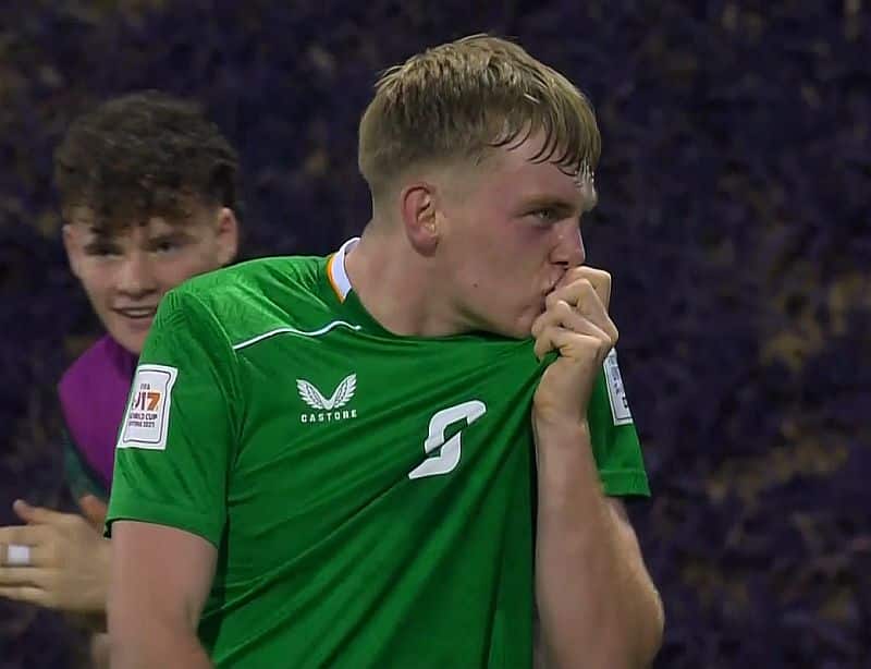 Michael Noonan celebrating a goal by kissing the crest on his green Republic of Ireland jersey.