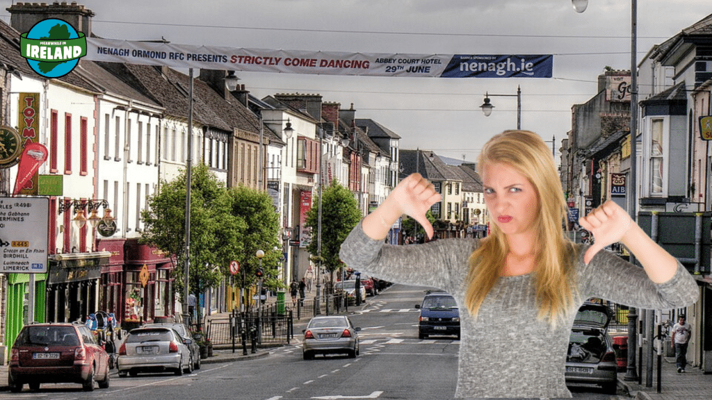 A humorous composite image featuring a street scene in Nenagh town centre with a blonde woman in the foreground giving a "thumbs down" gesture with both hands and a disgusted facial expression.